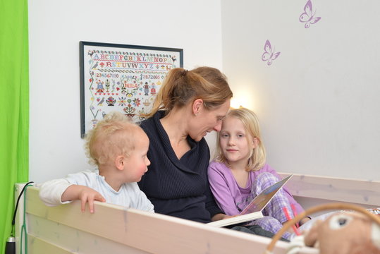 Mutter lie&szlig;t Kindern im Bett eine Geschichte vor