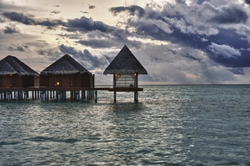 Dramatic sky in the Maldives with overwater bungalows