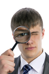 Young man looks through a magnifying glass