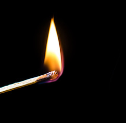 Burning match over black background