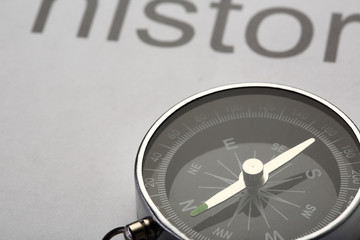 History book and compass on black