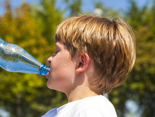 young boy drinks water out of a bottle