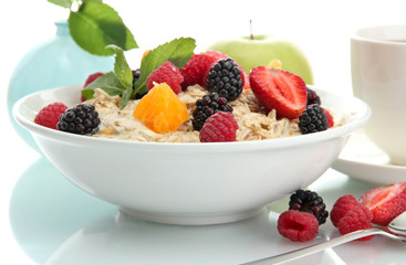 tasty oatmeal with berries and cup of tea, isolated on white