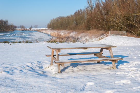Freshly fallen snow on a wooden picnic table and bench - Powered by Adobe