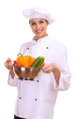 Portrait of young woman chef with vegetables isolated on white