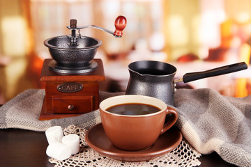 cup of coffee with scarf and coffee mill on table in room