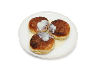 Три сырника со сгущенкой на тарелке