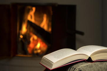 Peaceful and warm image of a open book by fireplace.