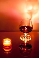 Ein Glas mit Alkohol und ein Teelicht 