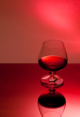 Ein Glas mit Alkohol vor rotem Hintergrund
