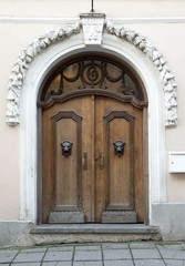 Old brown wooden door with metal panther heads ornaments