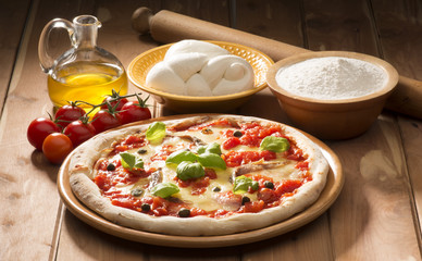 pizza with ingredients on wooden table