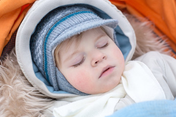 Adorable baby boy in winter clothes sleeping in stroller