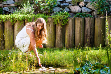 Woman sitting at pond in her garden