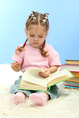 cute little girl with colorful books, on blue background
