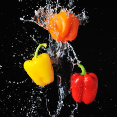 Three peppers water splash on black