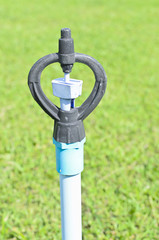Irrigation system throwing water drops on green grass