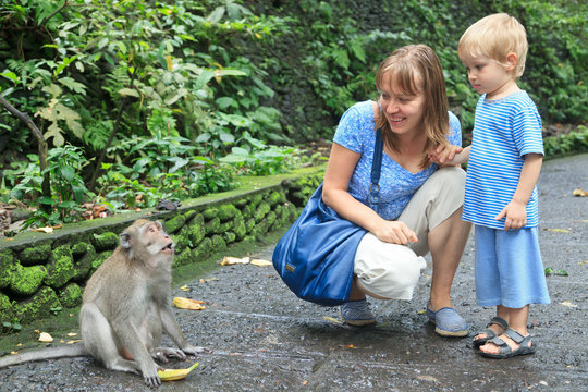 mother and son feeding wild monkey