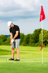 Young golf player on course putting to the hole