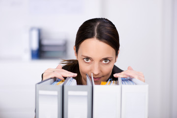 frau im büro schaut über aktenordner