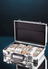 Suitcase with 100 dollar bills on dark color background
