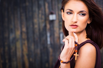 beautiful girl with christian beads against old wooden wall