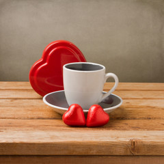 Coffee cup with heart shape chocolate on wooden table