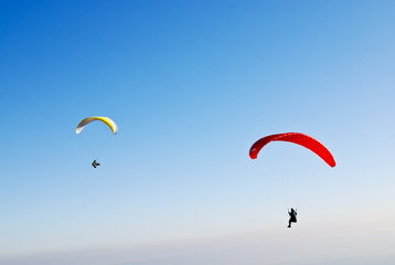 Gelber und roter Paragleiter am Himmel