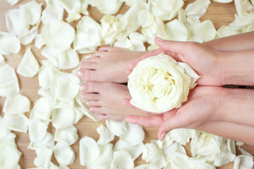Obraz na płótnie Canvas tanned hands and feet in spa with rose flowers and petals