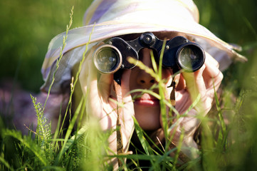 Young woman looking through binoculars in grass