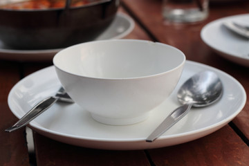 An empty cup with plate, fork and spoon on a wooden table