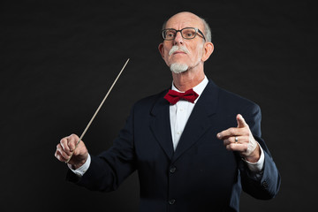 Senior conductor wearing suit. Studio shot.