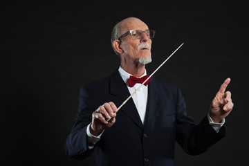 Senior conductor wearing suit. Studio shot.