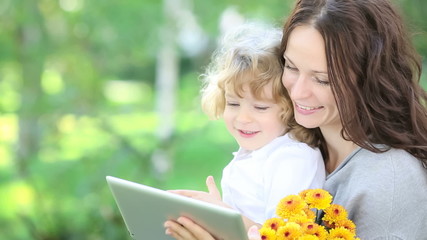Happy family using tablet PC outdoors in spring park