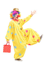 Full length portrait of a happy clown holding a bag and walking