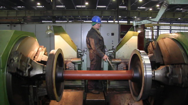 Worker processing steel on a lathe in factory