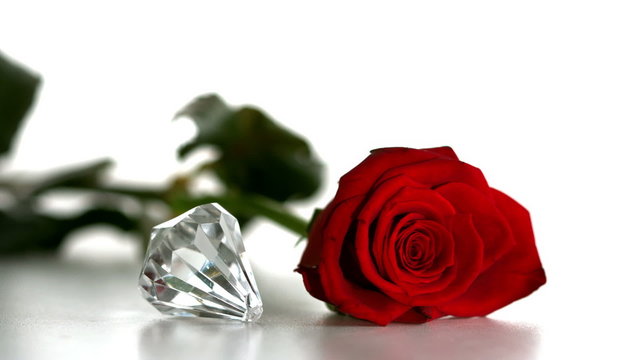 Diamond spinning beside red rose on white background