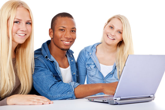 Drei attraktive junge Personen sitzen gemeinsam vor Laptop