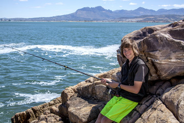 young teenage boy fishing by the sea