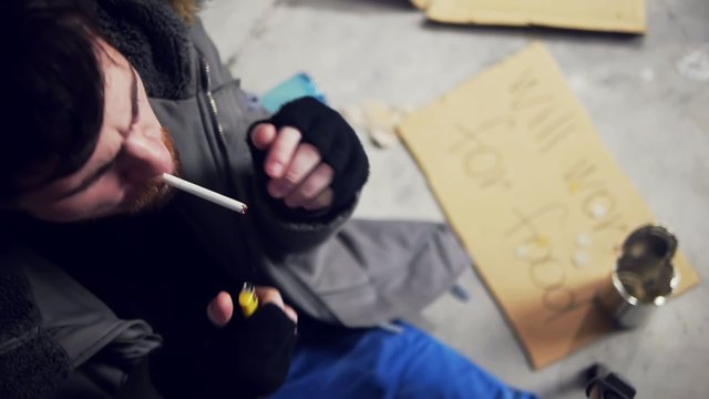 homeless man sitting on the floor and smoking cigarette