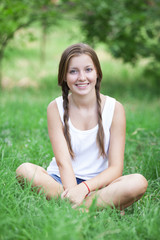 Naklejka na ściany i meble Piękna nastolatka w parku na zielonej trawie.