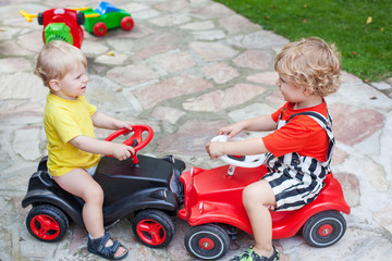 Naklejka premium Two little brothers toddlers playing with cars