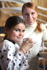 Little girl drinking from large mug at breakfast