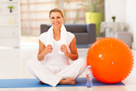 mature woman resting on exercise mat after fitness workout