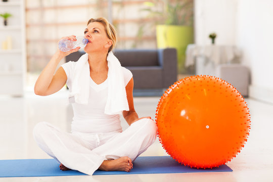 Fit Mature Woman Drinking Water After Exercise At Home