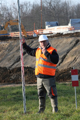 Man on construction site holding pole