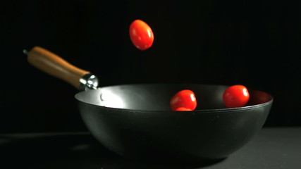 Cherry tomatoes falling into wok - Powered by Adobe