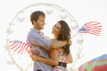 Caucasian couple holding American flags and enjoying carnival