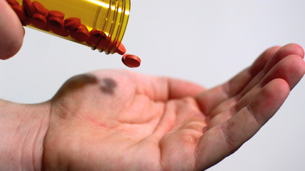 Red tablets being poured into open palm - Powered by Adobe