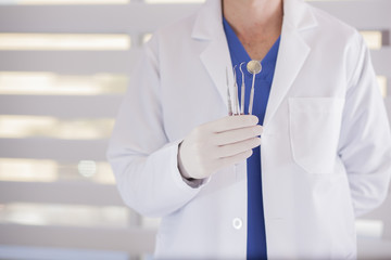 Close up of a young male dentist holding some instruments